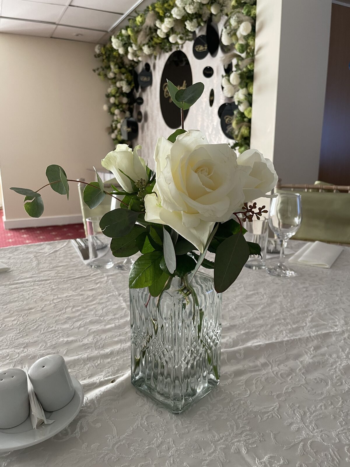 Single white rose bud vase with foliage